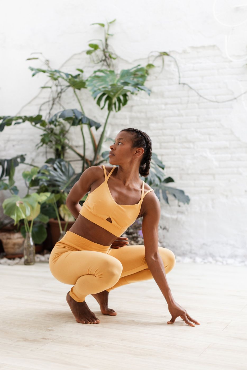 Nina en cuclillas con ropa amarilla junto a unas plantas
